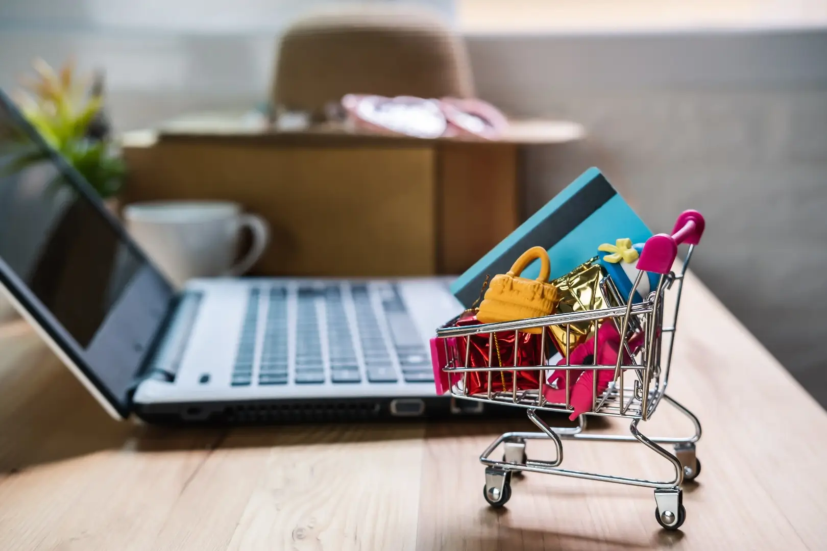 A miniature shopping cart beside a laptop representing online shopping